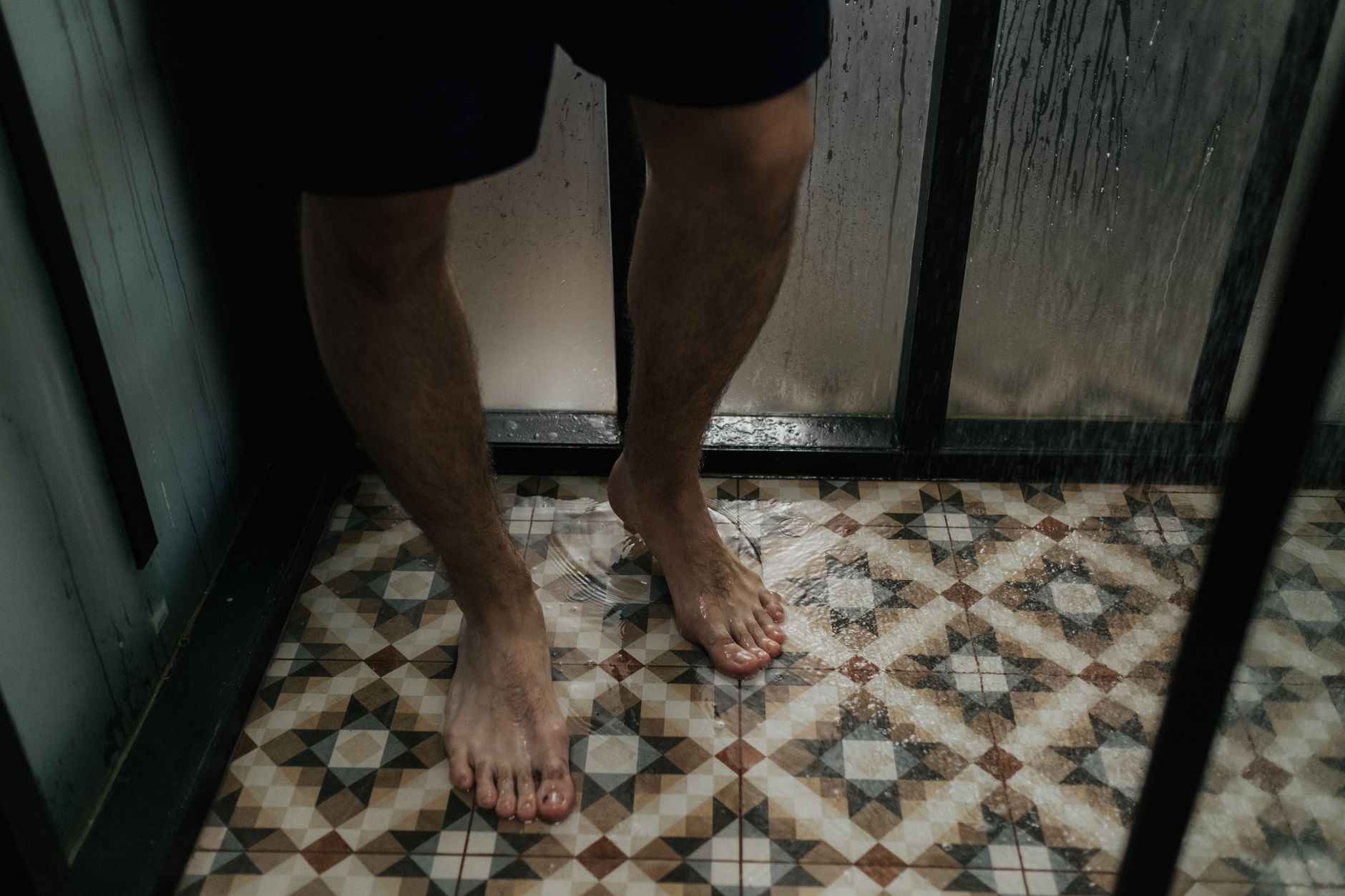 Pieds nus sous la douche sur un carrelage mouillé, terrain des mycoses des pieds