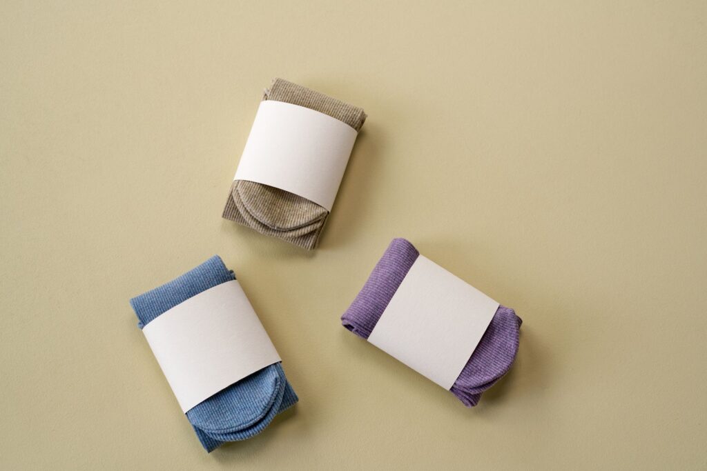 Trois paires de chaussettes pliées, bleues, violettes et grises, sur fond clair.