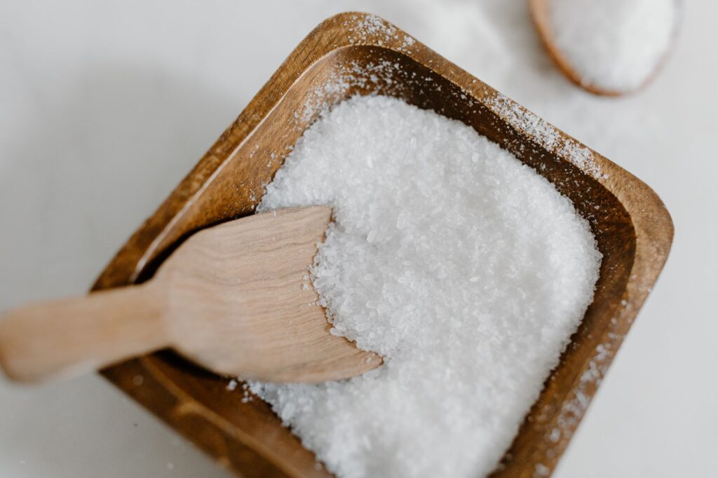 Gros plan de sel blanc dans un bol en bois avec une cuillère.