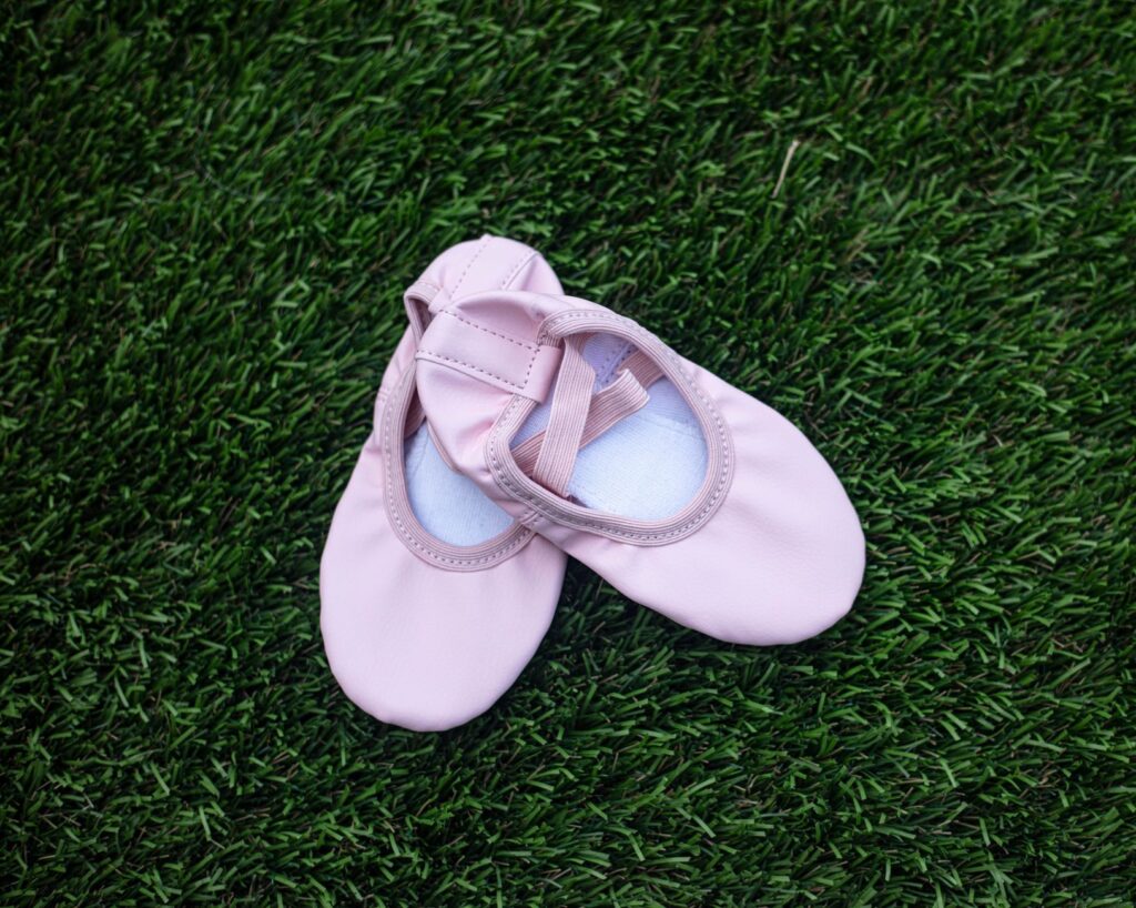 Une paire de chaussons de ballet roses sur de l'herbe verte.