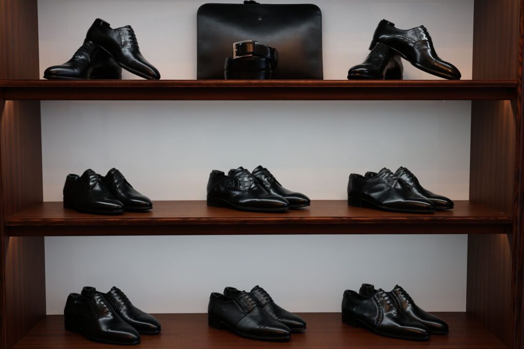 Chaussures élégantes en cuir noir sur des étagères en bois.