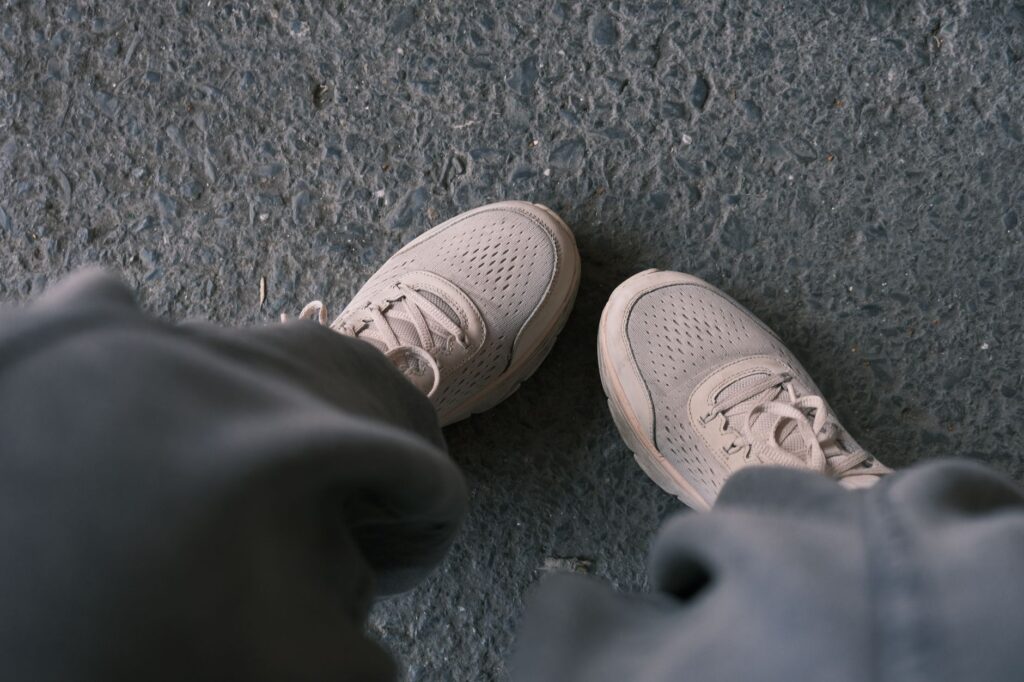 Vue plongeante sur une paire de chaussures de marche claires sur le bitume.