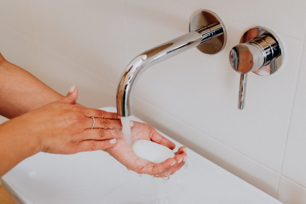 Une personne lavant ses mains avec du savon sous un robinet d'eau.